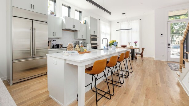 A modern kitchen with a large island, stainless steel appliances, and a dining area with bar stools.