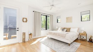 A bedroom with a bed, a ceiling fan, a window, and a door.