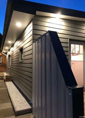 A modern house with a garage door, a small window, and a light fixture on the exterior wall.