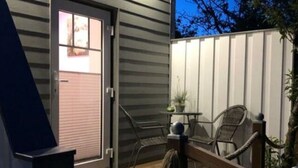 A wooden deck with a railing, a door leading to a garage, and two chairs. - Romantic Apartment Near Seabeach (Büsum)