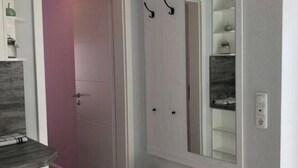 A hallway with a white door, a clock, and a mirror on the wall. - Romantic Apartment Near Seabeach (Büsum)