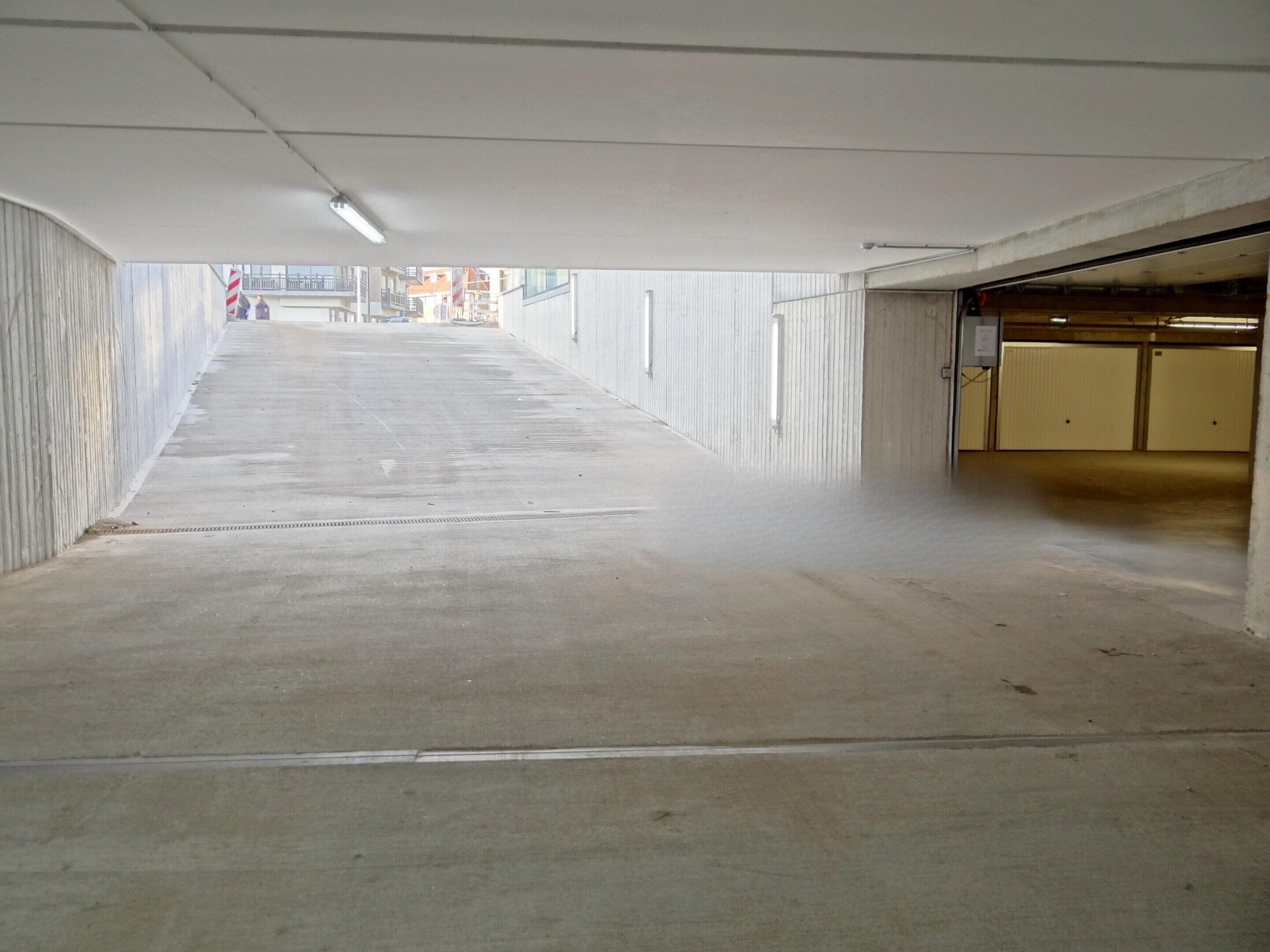 A long, empty corridor with concrete walls and a ceiling.