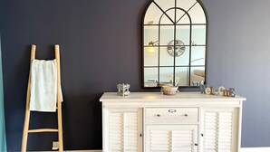 A room with a dark blue wall, a white vanity with drawers and a mirror, a wooden ladder, and a basket on the vanity. - Apartment in Nieuwpoort Near the Beach (Nieuwpoort)