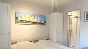 A bedroom with two beds, a shower, and a painting of sailboats on the wall. - Apartment in Nieuwpoort Near the Beach (Nieuwpoort)