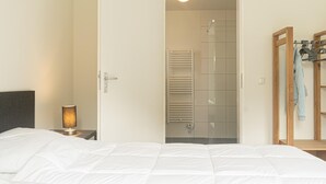 Een hotelkamer met een bed, een bedlamp, een houten kledingkast en een douchegedeelte.