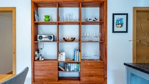 Ein Holzregal mit verschiedenen Gegenständen, darunter Bücher, ein Radio und Glaswaren.