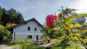 Ein zweigeschossiges Haus mit Garten-Terrasse, Essbereich und Schubkarre.