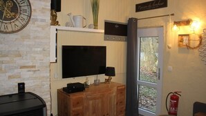 Un salon équipé d’un téléviseur à écran plat, d’un meuble en bois, d’une horloge et d’une enseigne sur laquelle on peut lire : « Maison du bonheur ».