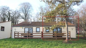 Un bâtiment d’un seul étage, doté d’un toit en tuiles, d’une clôture en bois et d’un banc.