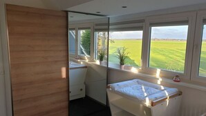 Une chambre avec une grande fenêtre, une armoire en bois, un lit et une petite table de chevet.