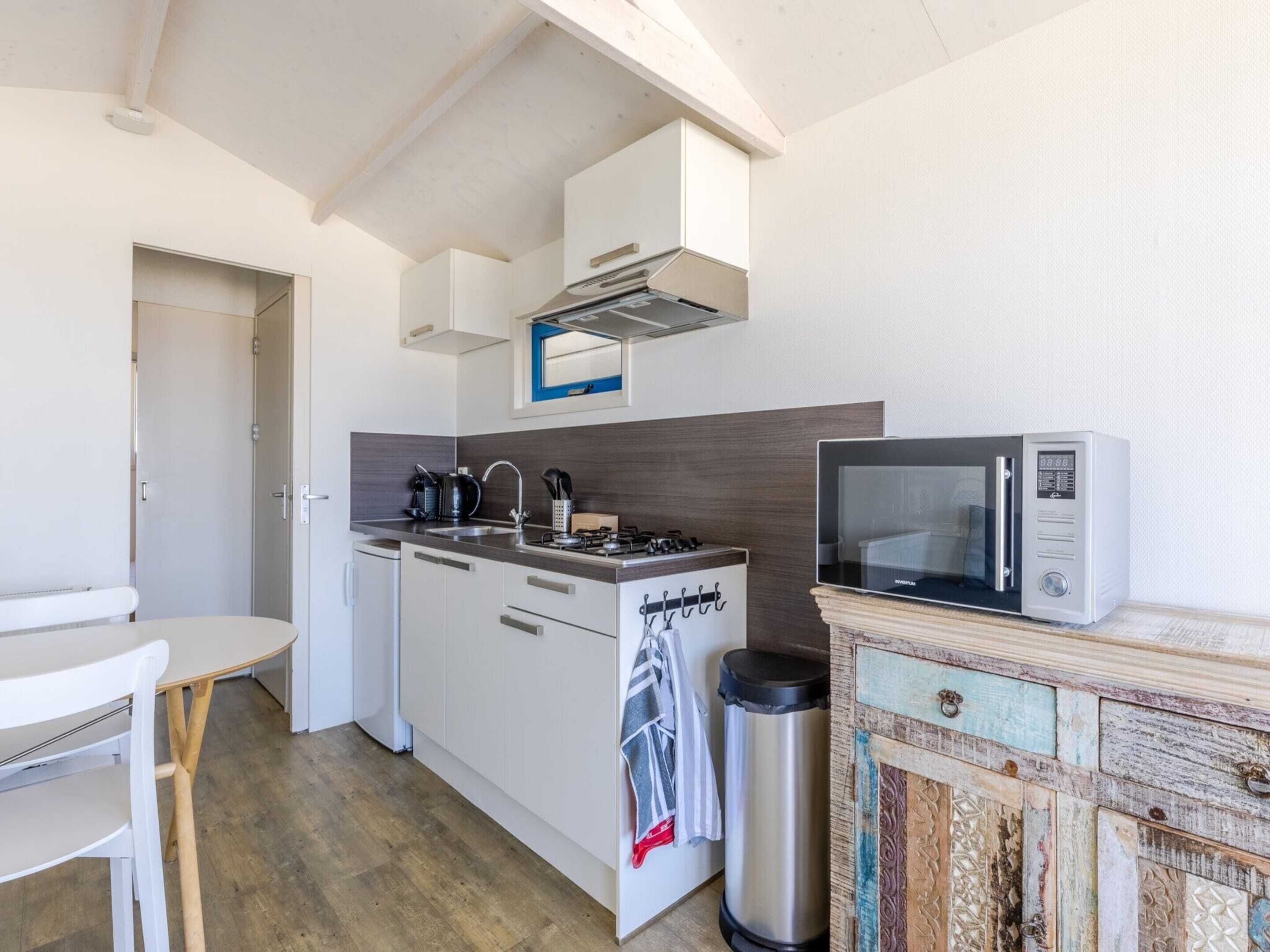 A compact kitchen with white cabinets, a microwave, a gas stove, and a sink.