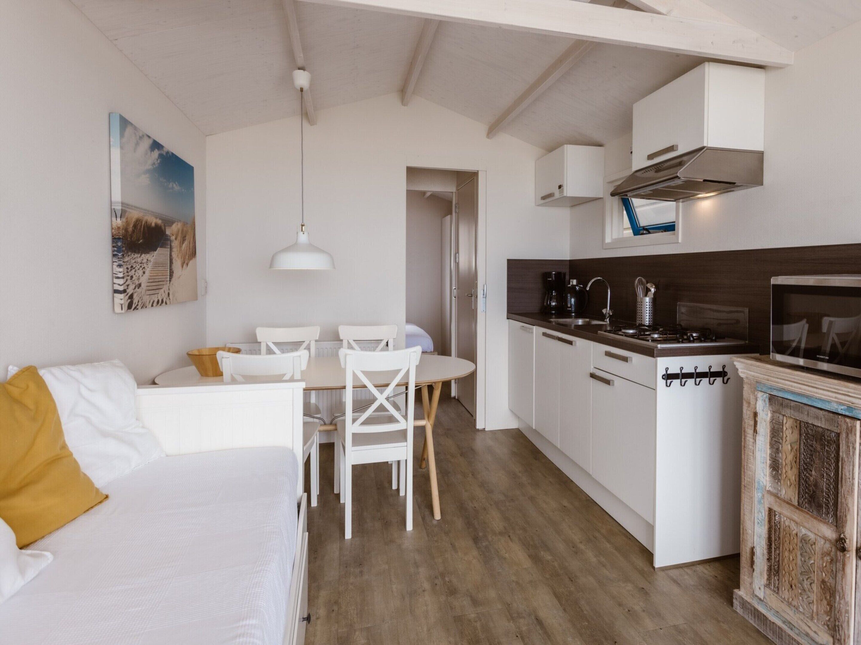 Ein kompakter Wohnraum mit Küchenzeile, Essbereich und Bett.