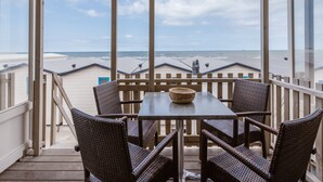 A balcony with a table and chairs, overlooking a beach with buildings in the background. - Holiday Home in Wijk aan Zee by the Beach (Wijk aan Zee)