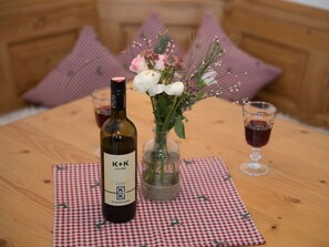 A bottle of wine, a glass of wine, and a vase with flowers on a table. - Lively Apartment in Bad Wiessee (Bad Wiessee)