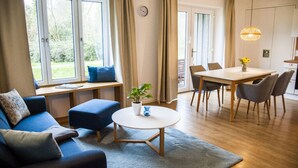 Een moderne woonkamer met een bank, een rond bijzettafeltje en een eethoek met een tafel en stoelen.