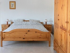 A wooden bed with a patterned bedspread, two nightstands with lamps, and a wooden wardrobe. - Serene Retreat in El Rafol (El Ràfol d'Almúnia)