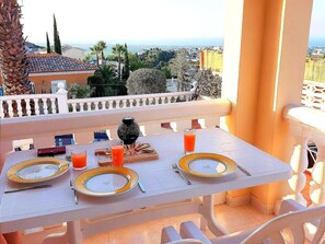 A dining table set with plates, cutlery, and glasses, overlooking a scenic view with palm trees and buildings. - Serene Retreat in El Rafol (El Ràfol d'Almúnia)