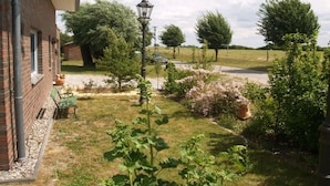Una casa de ladrillo con jardín, una farola y árboles al fondo.