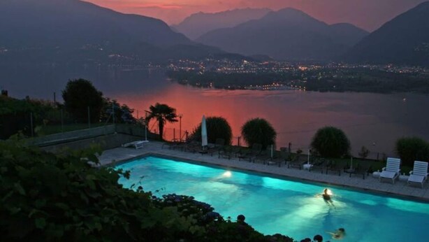 A swimming pool with a view of a lake and mountains at dusk. - Holiday Apartment Casa Chimp 5 (Gambarogno)