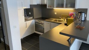 A modern kitchen with white cabinets, a stainless steel stove, and a black countertop. - Holiday Apartment Casa Chimp 5 (Gambarogno)