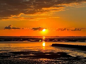 A sunset over a beach with calm waters reflecting the sky. - South in Haus Luttmoor (Nordstrand)