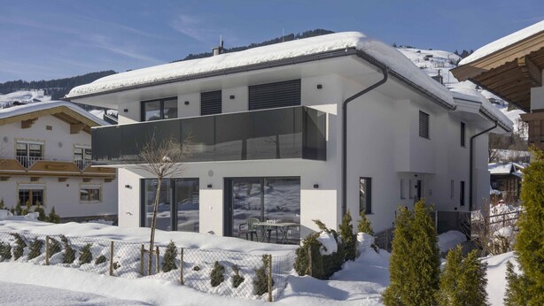 A modern two-story house with a balcony, surrounded by snow-covered landscape and trees. - Apartment in Brixen Near Ski Welt (Brixen im Thale)