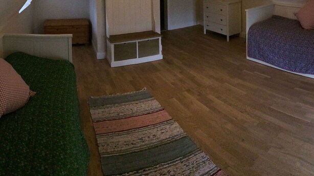 Een slaapkamer met een bed, een dressoir, een bankje en een kledingrek.