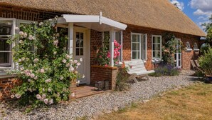 A traditional brick house with a thatched roof, a white porch, and a gravel driveway. - Appelhus Modern Retreat (Loit)