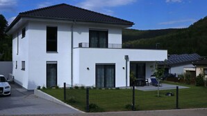 A modern two-story house with a white exterior, a balcony on the upper floor, and solar panels on the roof. - Haus Edith Modern Retreat (Lug)