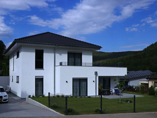 A modern two-story house with a white exterior, a balcony on the upper floor, and solar panels on the roof. - Haus Edith Modern Retreat (Lug)