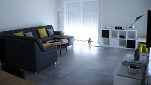 A modern living room with a sofa, coffee table, and a TV stand with shelves. - Haus Edith Modern Retreat (Lug)