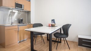 Una cucina compatta con mobili in legno, un forno a microonde, una macchina da caffè e un tavolo da pranzo con due sedie.