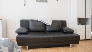 Un divano in pelle nera con una coperta, un armadio bianco e un quadro appeso al muro.