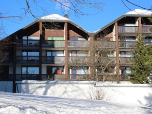A multi-story building with balconies, a snow-covered roof, and a clear blue sky. - Studio mit Terrasse in Winterberg (Winterberg)