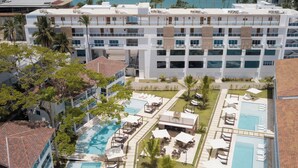 A resort with multiple swimming pools, sun loungers, and a view of the ocean.