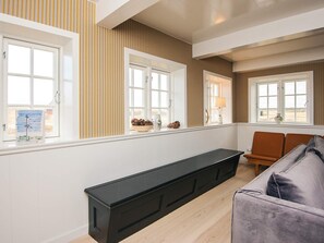 En moderne stue med en sort bænk, en grå sofa og et vindue med udsigt.