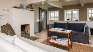 A living room with a fireplace, a sofa, a coffee table, and a bookshelf with books. - 6 Person Holiday Home in Fano (Fano)