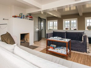 A living room with a fireplace, a sofa, a coffee table, and a bookshelf with books. - 6 Person Holiday Home in Fano (Fano)
