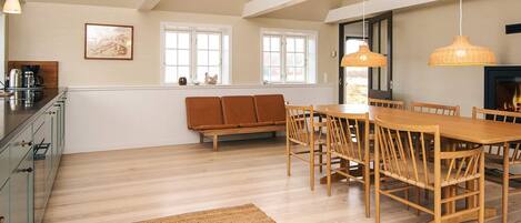 A spacious dining area with a wooden table and chairs, a bench, and a fireplace.