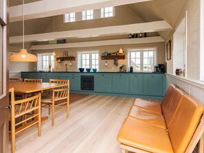 A spacious kitchen with teal cabinets, a wooden dining table, and a leather bench. - 6 Person Holiday Home in Fano (Fano)