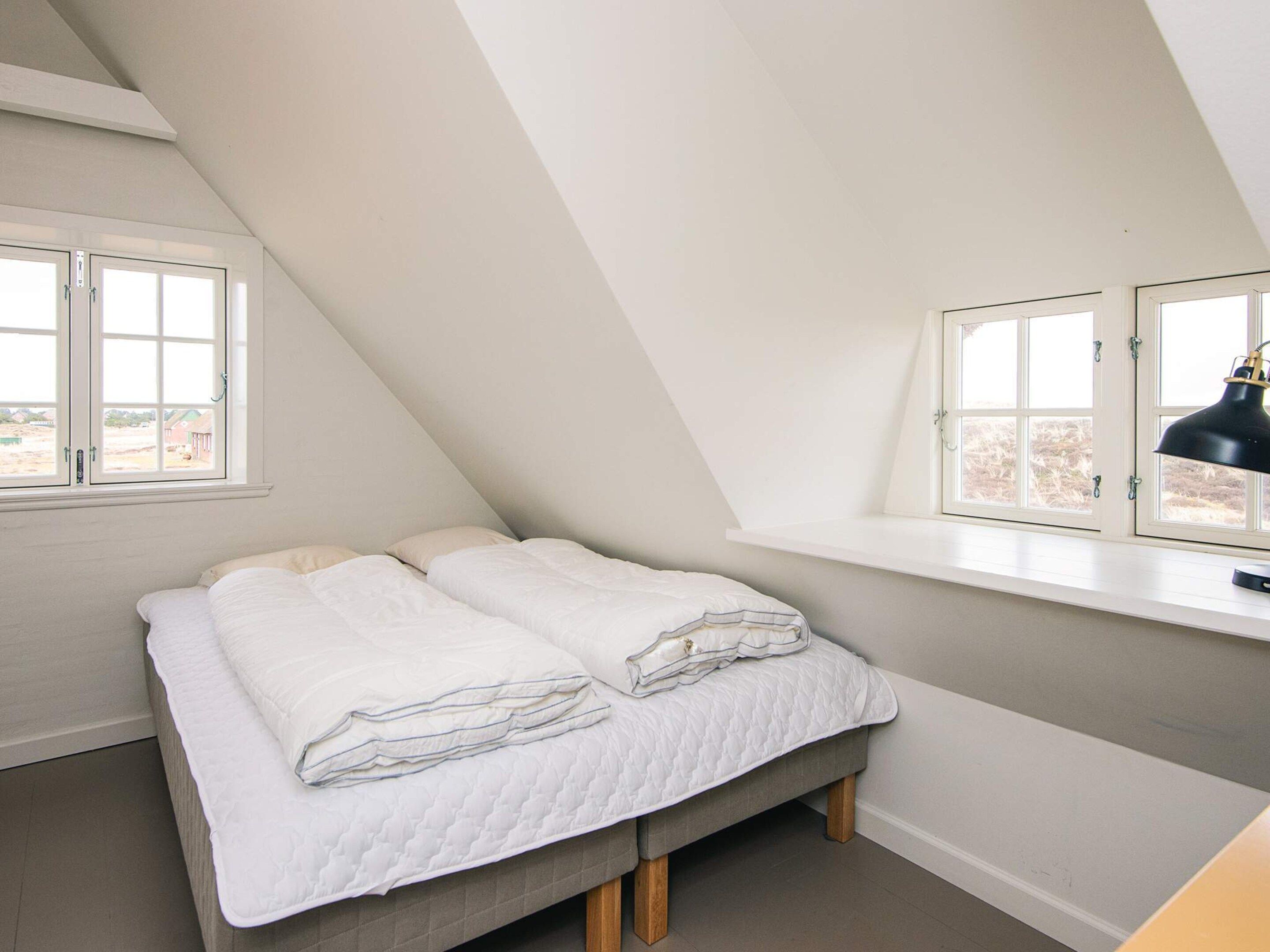 A bedroom with a loft bed, a desk, and a window with a view of buildings.