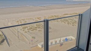 Une vue depuis un balcon donnant sur une plage, avec un ciel dégagé.