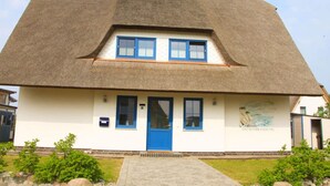 A traditional house with a thatched roof, a blue door, and a small porch. - Ostseebrandung - Haus Seestern (Dranske)