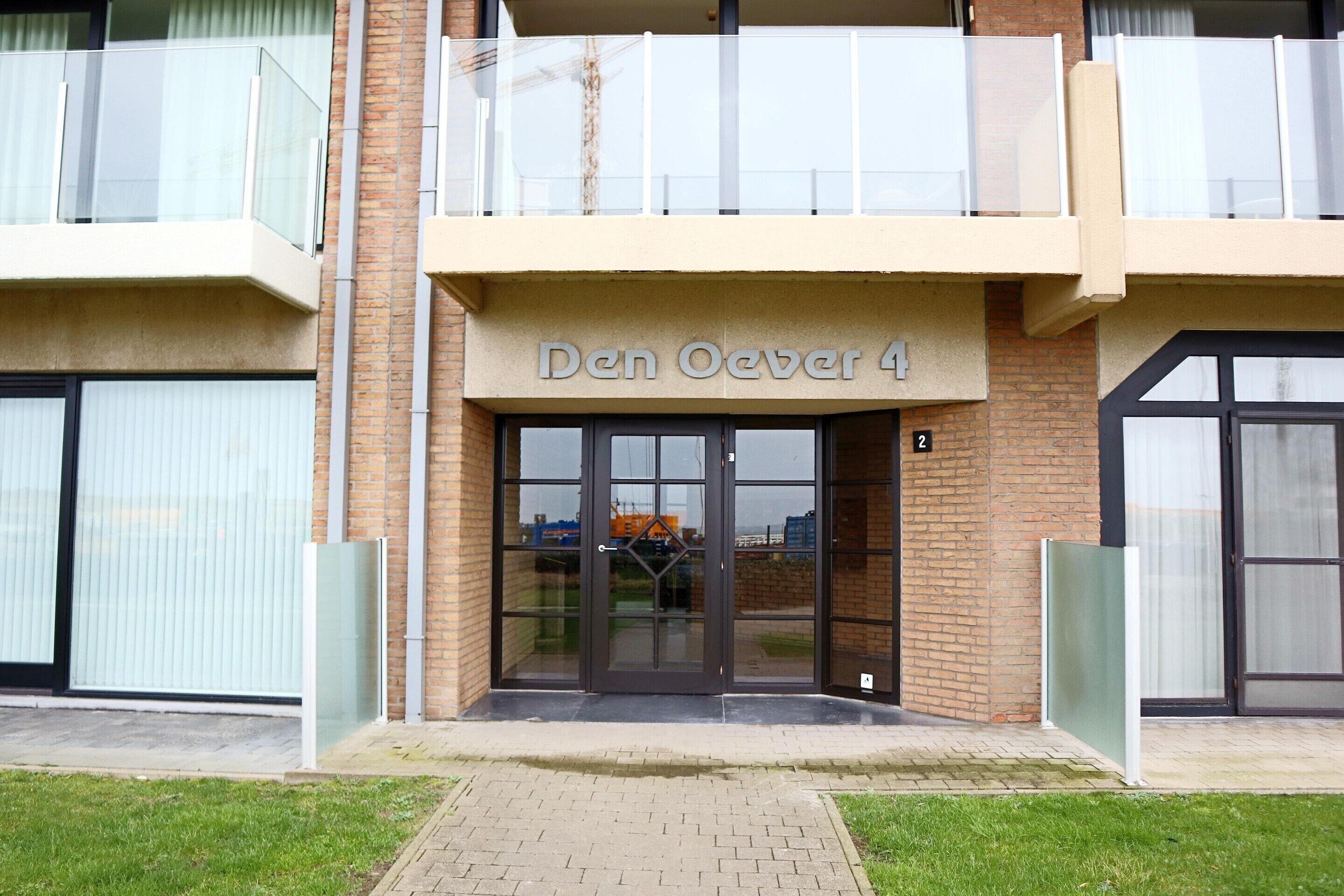 A building with a sign reading "Den Oever 4" and a glass entrance.