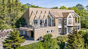 Een modern huis met een groot balkon, een garage en uitzicht op omliggende bomen.