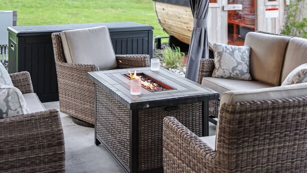 Eine Terrassengaststätte mit Korbmöbeln, einer Feuerstelle und einem überdachten Bereich mit Lichterketten.
