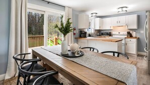 Eine moderne Küche mit weißen Schränken, einer Holz Arbeitsplatte und einem Essbereich mit Tisch und Stühlen.