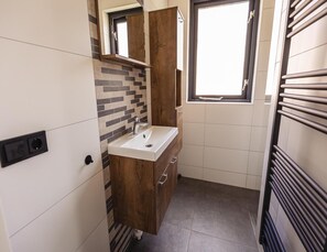 A compact bathroom with a modern sink, wooden vanity, and a window providing natural light. - Detached Home Nijmegen Lake View Sauna (Ewijk)