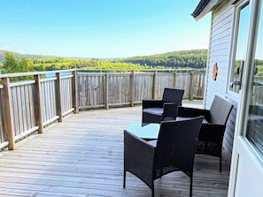 A wooden deck with a table and chairs, overlooking a forested area. - 4 Star Holiday Home in Uddevalla (Uddevalla)