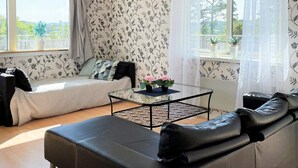 A modern living room with a sofa, a glass coffee table, and a view of the outdoors through large windows. - 4 Star Holiday Home in Uddevalla (Uddevalla)